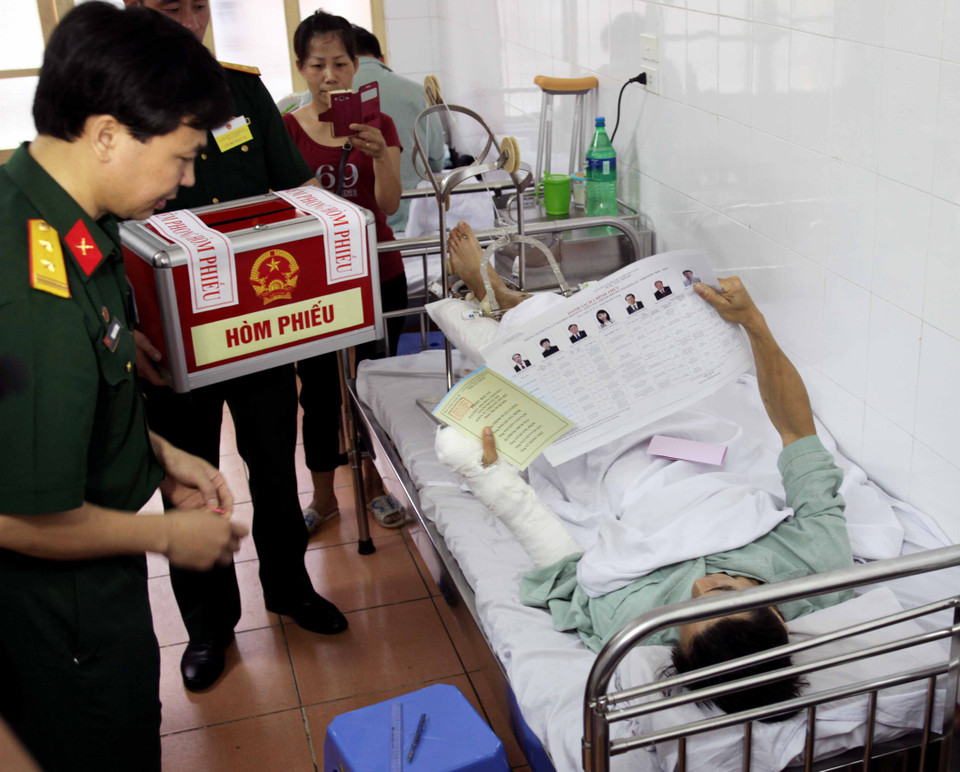 Ngay sau lễ khai mạc, tổ bầu cử đã dùng hòm phiếu phụ đến tận giường của những bệnh nhân nặng, không đủ sức khỏe đi bỏ phiếu tại các điểm bỏ phiếu cố định. (Ảnh: Doãn Đức/Vietnam+)