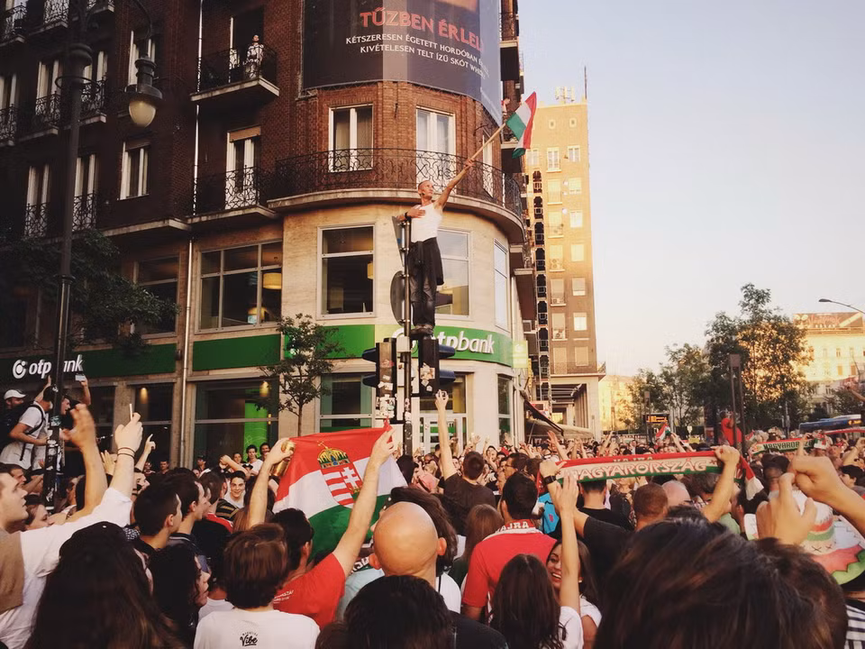 Sau trận hòa 3-3 với Bồ Đào Nha, hàng vạn người Hungary đã đổ ra đường ăn mừng chiến tích đội nhà lọt vào vòng 1/8 của EURO 2016. Một người đàn ông đã trèo lên cột đèn giao thông phất cờ trong sự phấn khích của người hâm mộ (Ảnh: Quốc Thịnh/Vietnam+)
