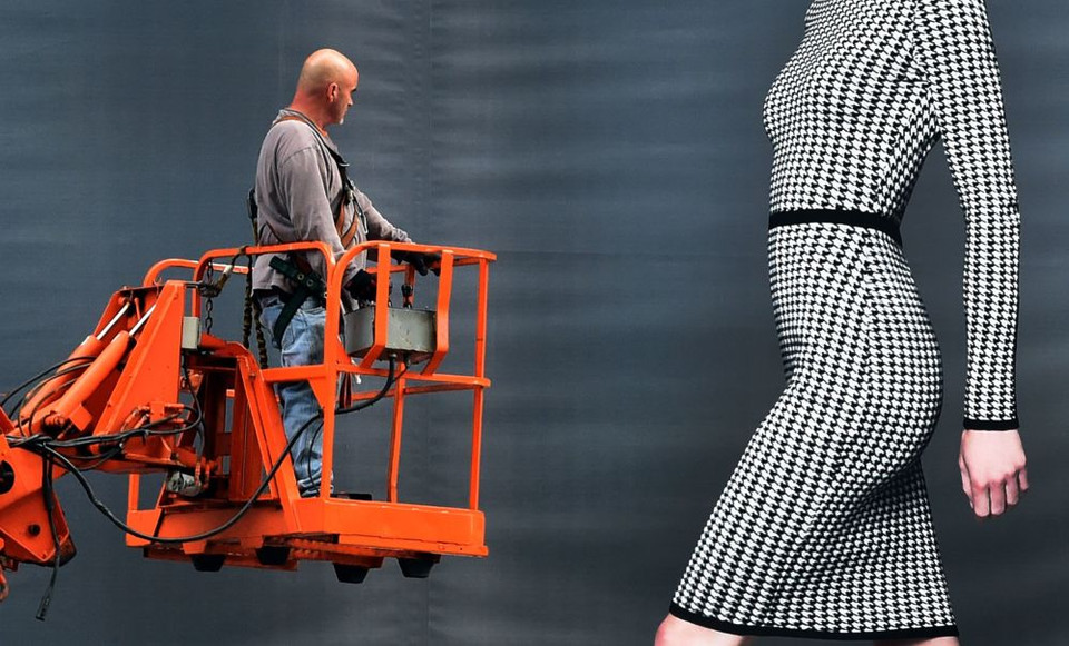 Một công nhân đứng trên thang máy bên cạnh một tấm biển quảng cáo cho thương hiệu Dressbarn ở Midtown Manhattan, Mỹ. (Nguồn: AFP)