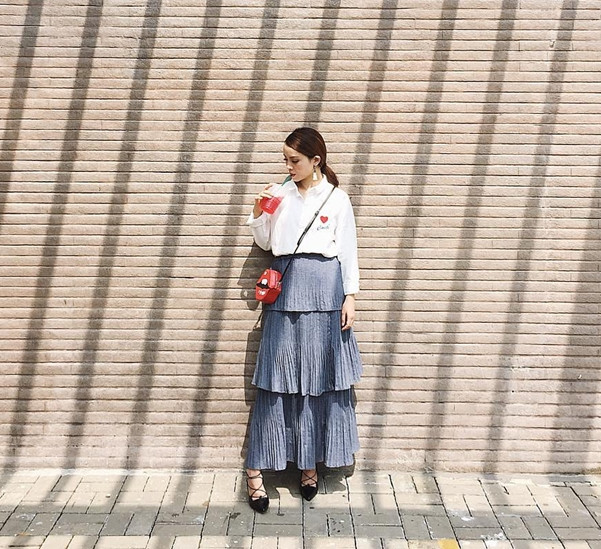 Cũng diện sơmi trắng, Yến Trang biến tấu ngẫu hứng cùng chân váy xếp tầng bồng bềnh. Cô nàng chọn giày buộc dây và thêm phụ kiện là chiếc túi hình đôi môi nghịch ngợm. 