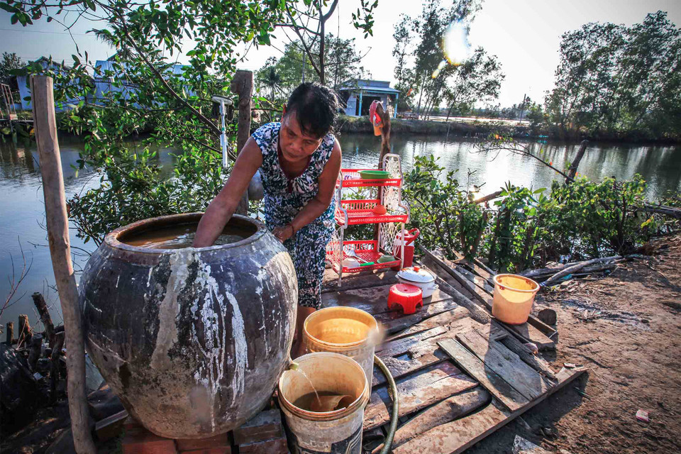 Gia đình bác Trần Thị Thu, ấp Bảy Biển, xã Nam Thái A, huyện An Biên, Kiên Giang đang rửa phèn bám lại trong chiếc lu mà gia đình bác lọc nước dùng để sinh hoạt từ nguồn nước ngầm. (Ảnh: Trọng Đạt/TTXVN)