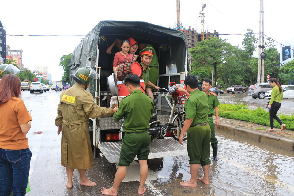 Đội cứu hộ Công an thành phố Vinh hỗ trợ những người dân bị mắc nạn do ngập nước. (Ảnh: Bích Huệ/TTXVN)