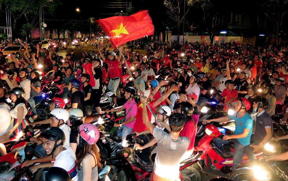 Một cổ động viên cuồng nhiệt vẫy cờ Việt Nam ăn mừng giữa dòng xe chật cứng.