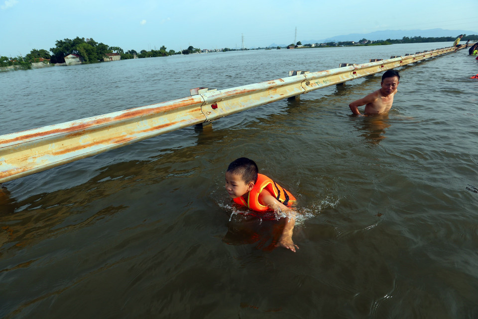 Nhiều người dân ở các thôn lân cận đã đi bắt cá và cho trẻ ra bơi lội khiến cả đoạn đường như trở thành một 'bể bơi lộ thiên.' (Ảnh: Huy Hùng/TTXVN)