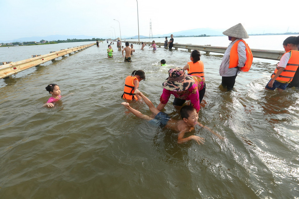 Người dân xã Cấn Thượng đưa trẻ em ra đường tỉnh lộ tập bơi. (Ảnh: Huy Hùng/TTXVN)