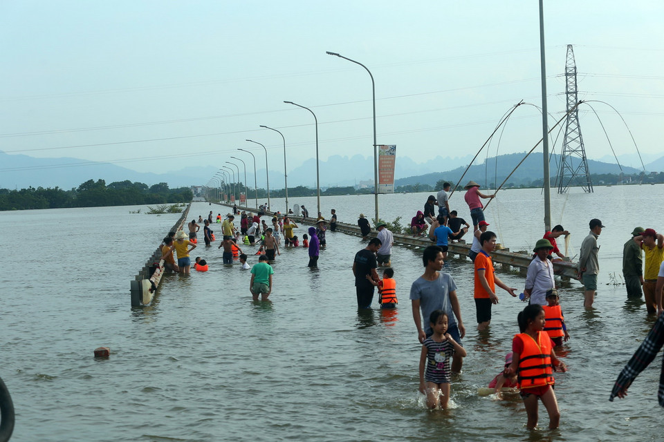 Cảnh tượng trẻ tập bơi, người lớn đánh cá trên đường tỉnh lộ 421B. (Ảnh: Huy Hùng/TTXVN)