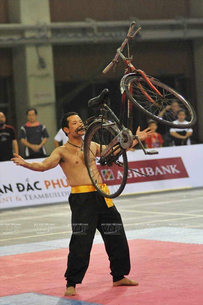 Dùng hàm răng nhấc bổng chiếc xe đạp. (Ảnh: Trần Thanh Giang/Báo ảnh Việt Nam)