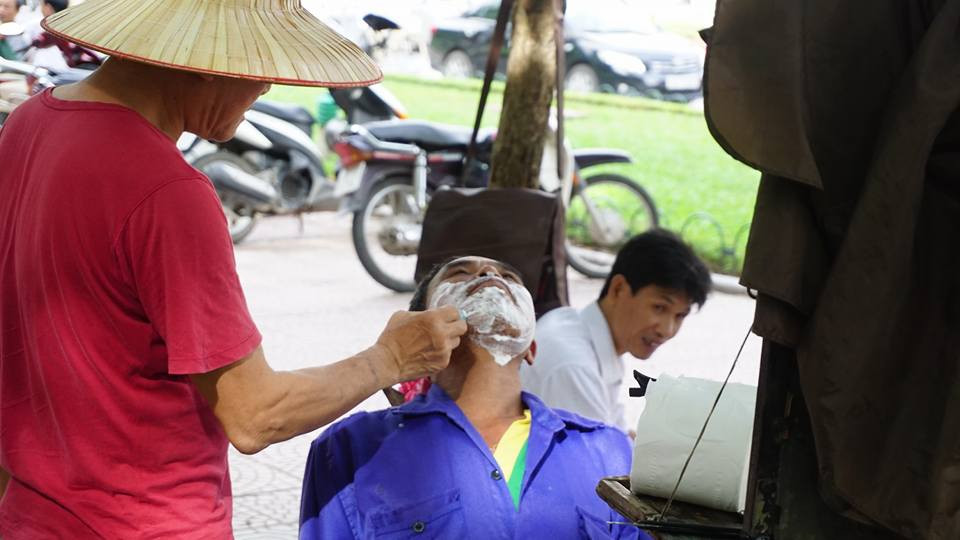 Một vị phụ huynh tranh thủ "tút tát" dung nhan trong lúc chờ đợi. (Ảnh: Võ Phương/Vietnam+)