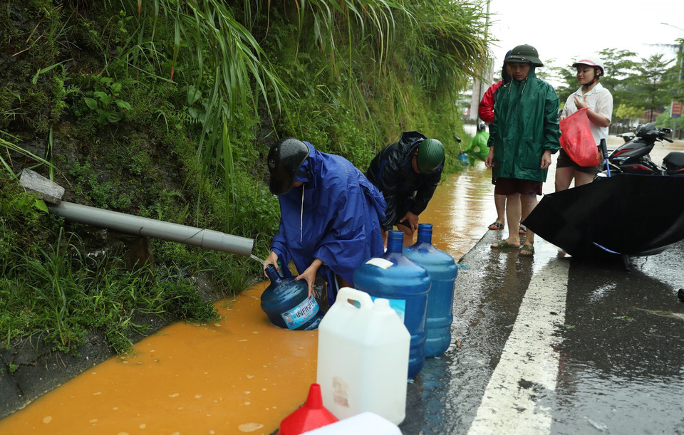 Người dân thành phố Lào Cai vất vả để lấy được đầy can nước được chảy ra từ khe núi. (Ảnh: Quốc Khánh/TTXVN)