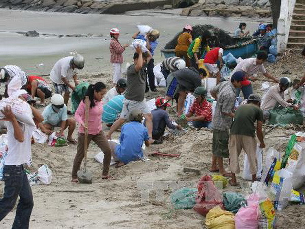 Người dân xúc cát vào bao tại bãi biển Nguyễn Tất Thành (Đà Nẵng) để chuyển về chống bão cho nhà cửa. (Ảnh: Văn Sơn/TTXVN)