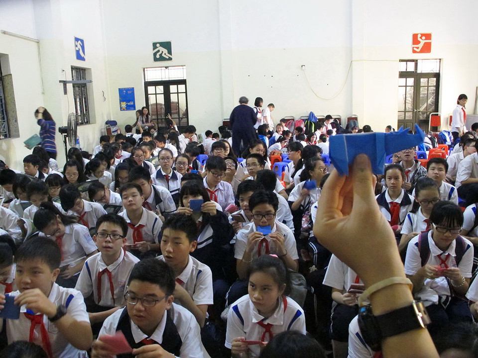 Các anh chị tình nguyện viên đang dạy các em học sinh cách tạo nên chú tê giác bằng nghệ thuật gấp giấy Origami. (Ảnh: Tiến Đạt/Vietnam+)