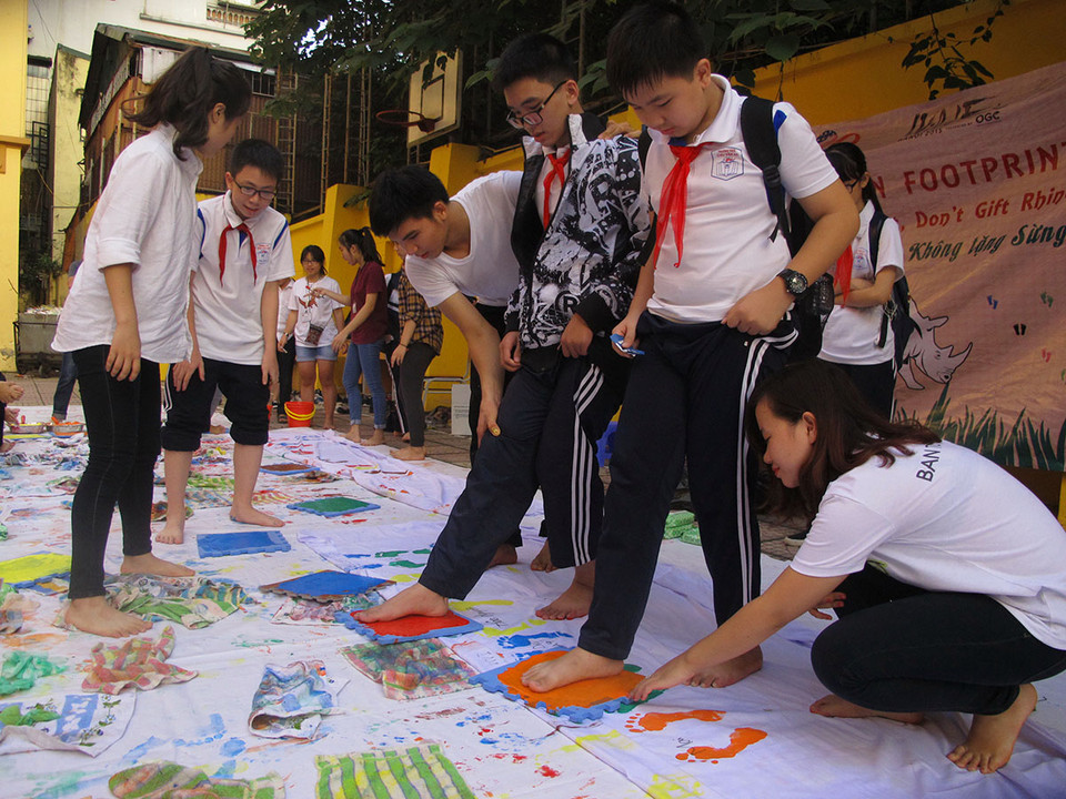 In dấu chân lên tấm vải trắng, một hoạt động để truyền tải thông điệp 'không sử dụng, không chấp nhận và không dùng sừng tê giác làm quà tặng.' (Ảnh: Tiến Đạt/Vietnam+)