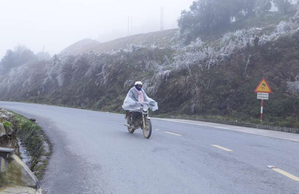 Người đi xe máy vẫn phải mặc áo mưa dù trời đã hết mưa khi đi qua khu vực đèo Ô Quý Hồ để chống chọi với giá rét 0-1 độ C. (Ảnh: Quý Trung/TTXVN)
