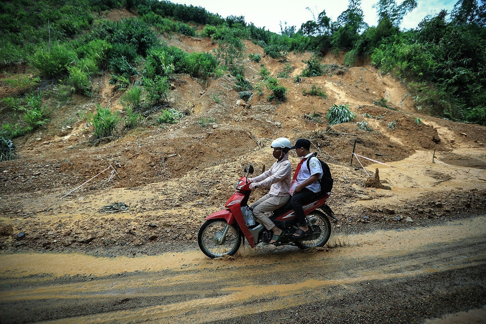 Người dân Đà Bắc đưa đón con học về qua những điểm sạt lở đất đầy rủi ro trên đường tỉnh 433. (Ảnh: Trọng Đạt/TTXVN)