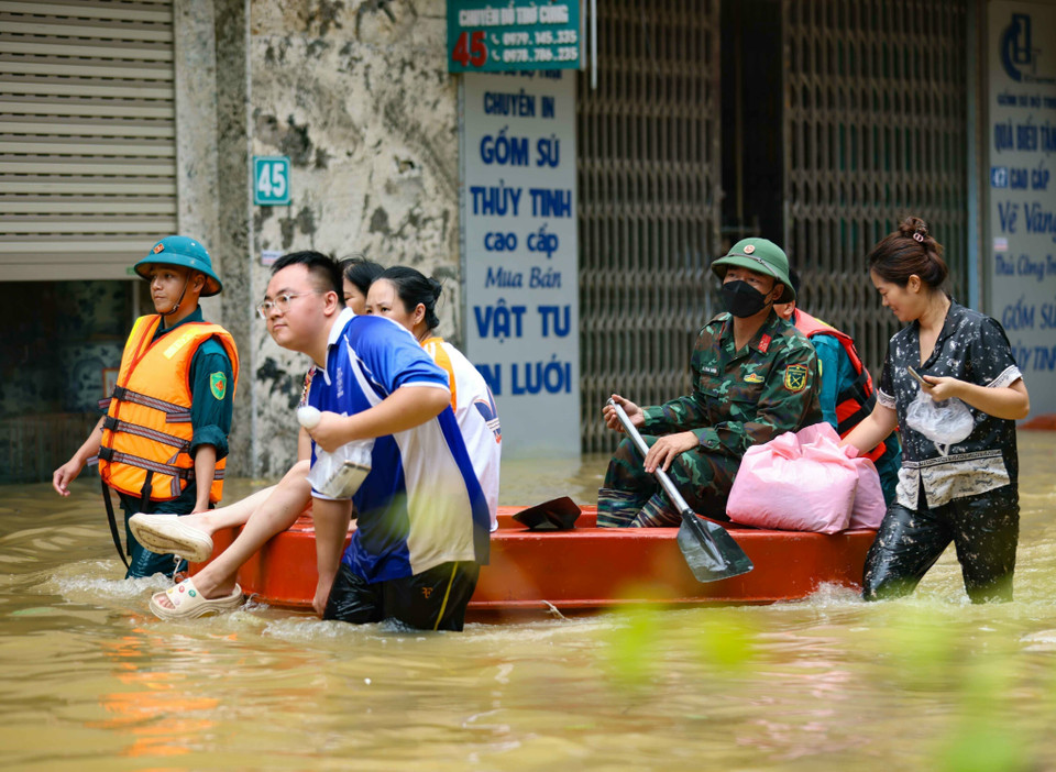 Hỗ trợ người dân xã Bát Tràng, huyện Gia Lâm di chuyển ra khỏi vùng ngập lụt. (Ảnh: Thanh Tùng/TTXVN)