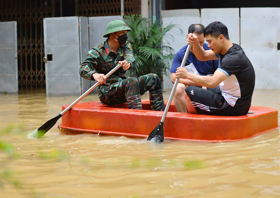 Giúp người dân di chuyển ra khỏi vùng ngập lụt. (Ảnh: Thanh Tùng/TTXVN)