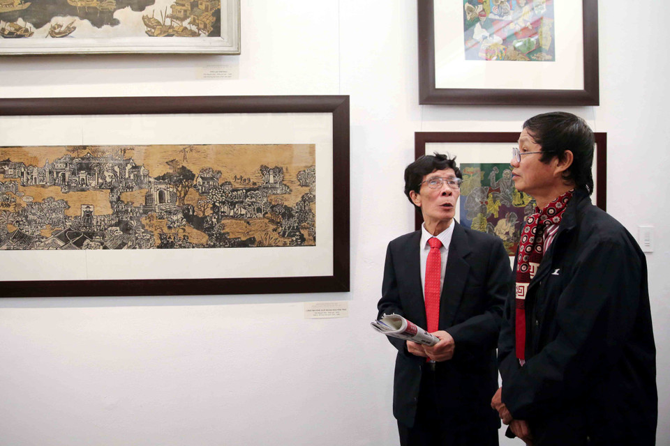 Họa sỹ Trần Nguyên Đán (bên trái) giới thiệu với công chúng các tác phẩm của mình. (Ảnh: Ngọc Tùng/Vietnam+)