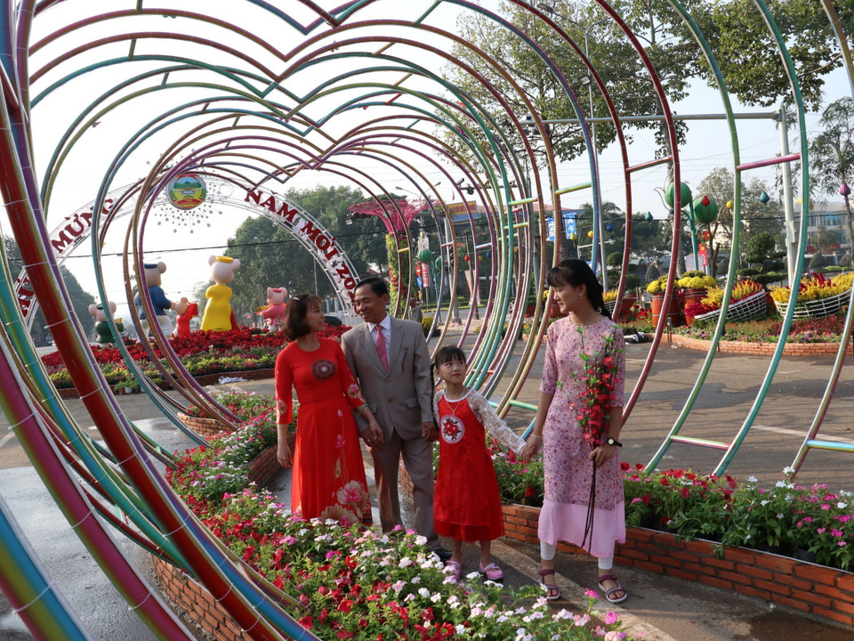 Người dân ghi lại những khoảnh khắc đẹp tại đường hoa “Vui Xuân” trên đường Hùng Vương, thành phố Đồng Xoài, tỉnh Bình Phước. (Ảnh: Dương Chí Tưởng/TTXVN)