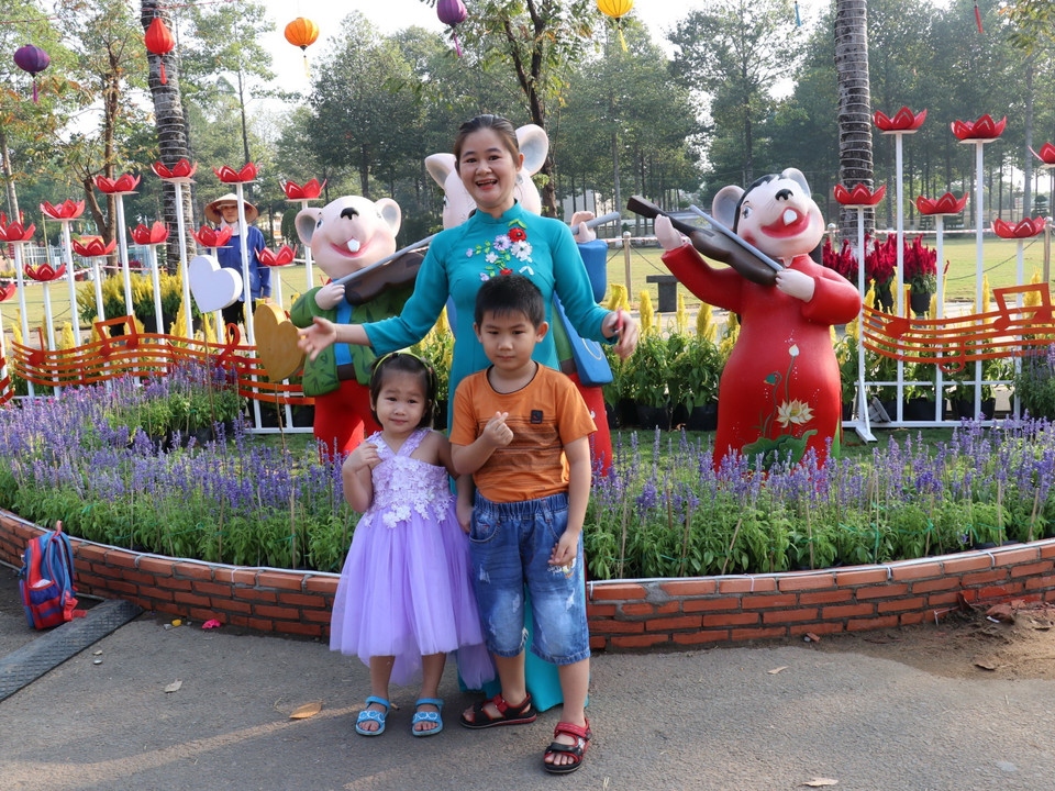 Người dân ghi lại những khoảnh khắc đẹp tại đường hoa “Vui Xuân” trên đường Hùng Vương, thành phố Đồng Xoài, tỉnh Bình Phước. (Ảnh: Dương Chí Tưởng/TTXVN)