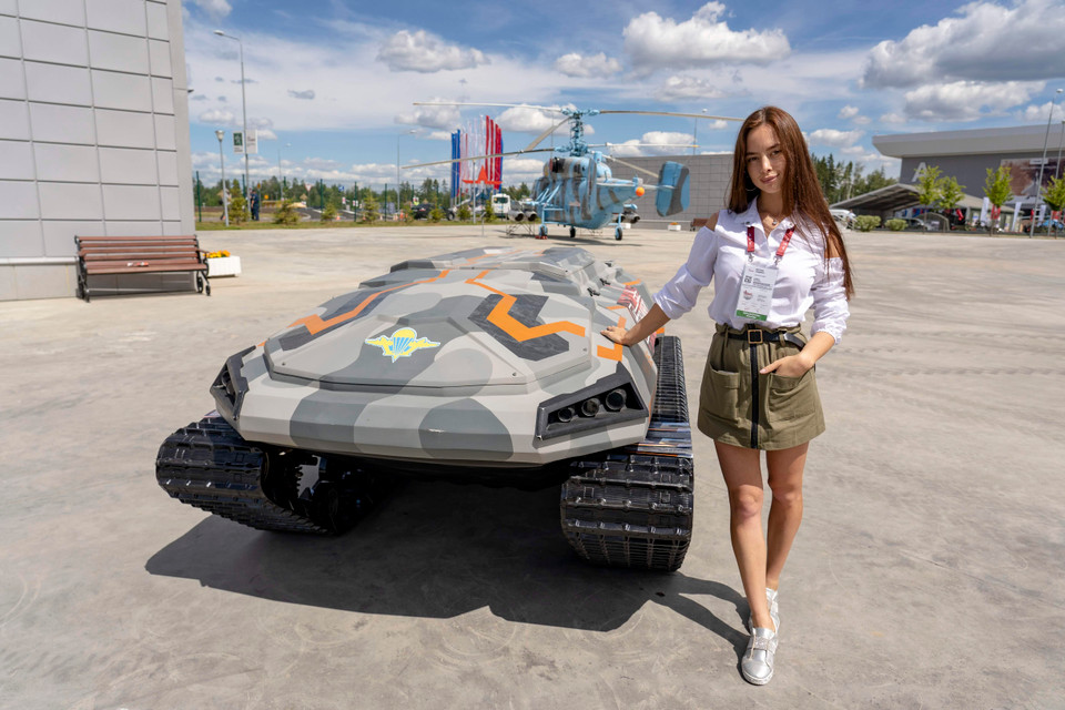 Thiếu nữ Nga tạo dáng bên một thiết bị chiến đấu không người lái được thiết kế cho các đơn vị Đổ bộ đường không VDV của Nga. (Ảnh: Hồng Quân)