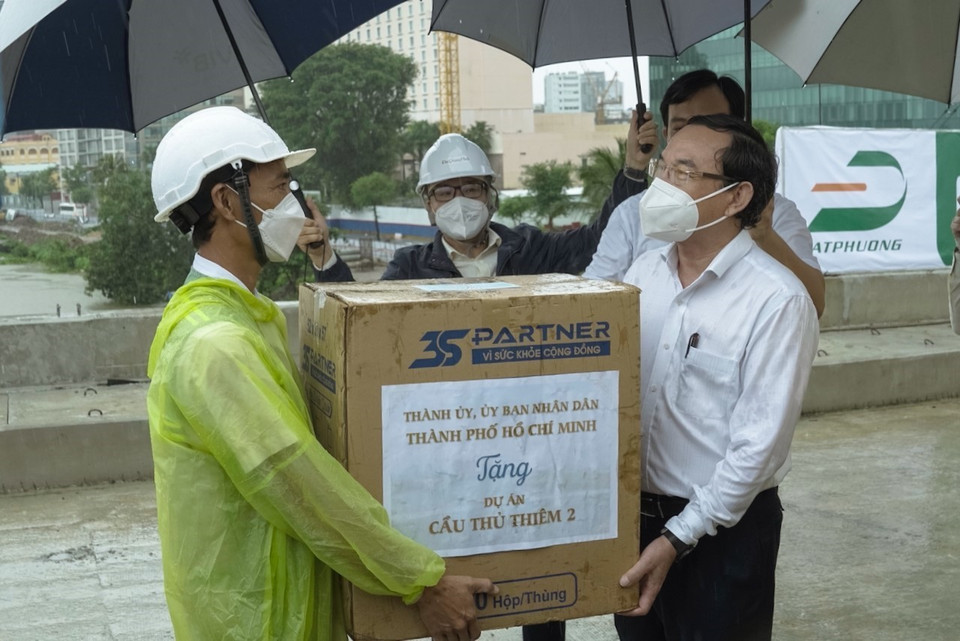 Bí thư Thành ủy Thành phố Hồ Chí Minh Nguyễn Văn Nên (phải) tặng quà cho công nhân thi công dự án cầu Thủ Thiêm 2, ngày 30/9/2021. (Ảnh: Tiến Lực/TTXVN)