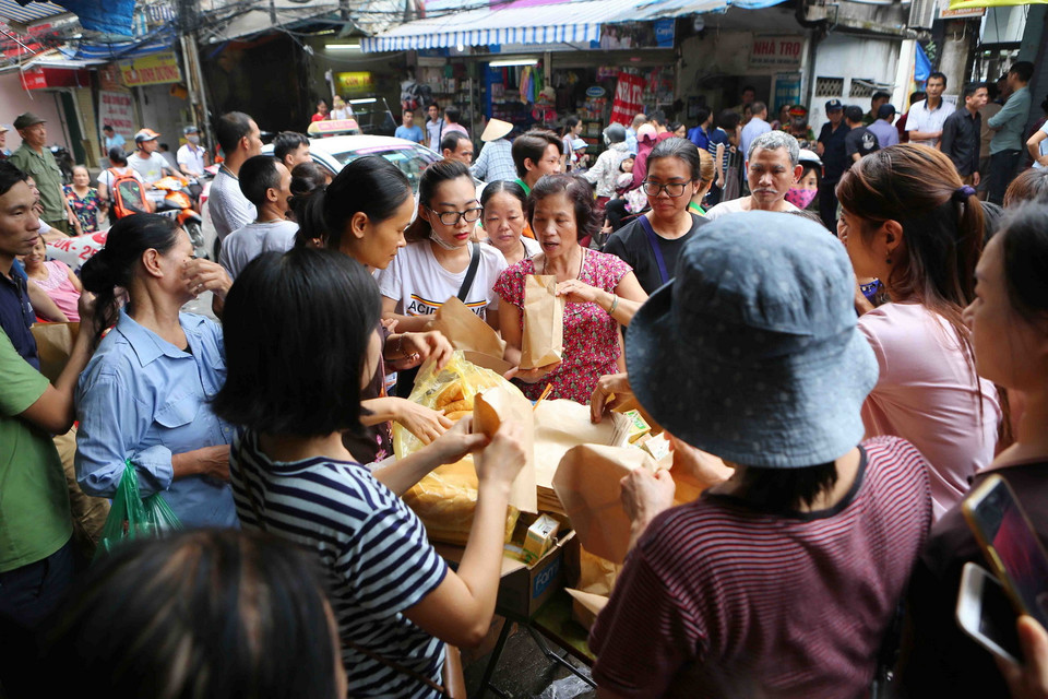 Người dân nhận bánh mỳ và cháo hỗ trợ từ các nhà hảo tâm. (Ảnh: Thành Đạt/TTXVN)