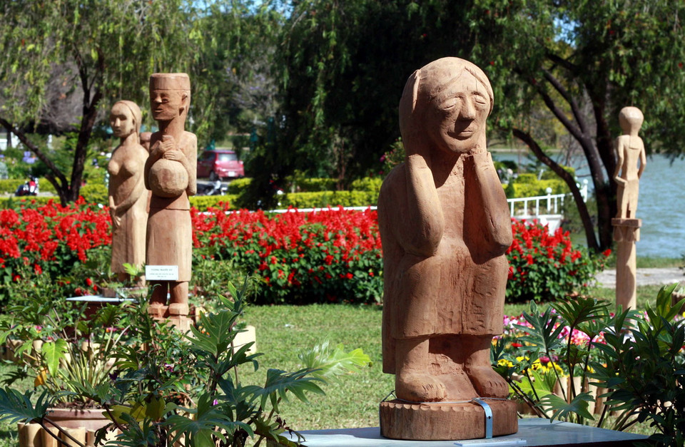 Tượng gỗ Tây Nguyên được sắp đặt chung với hoa Đà Lạt trong không gian “Đà Lạt bốn mùa hoa." (Ảnh: Nguyễn Dũng - TTXVN) 