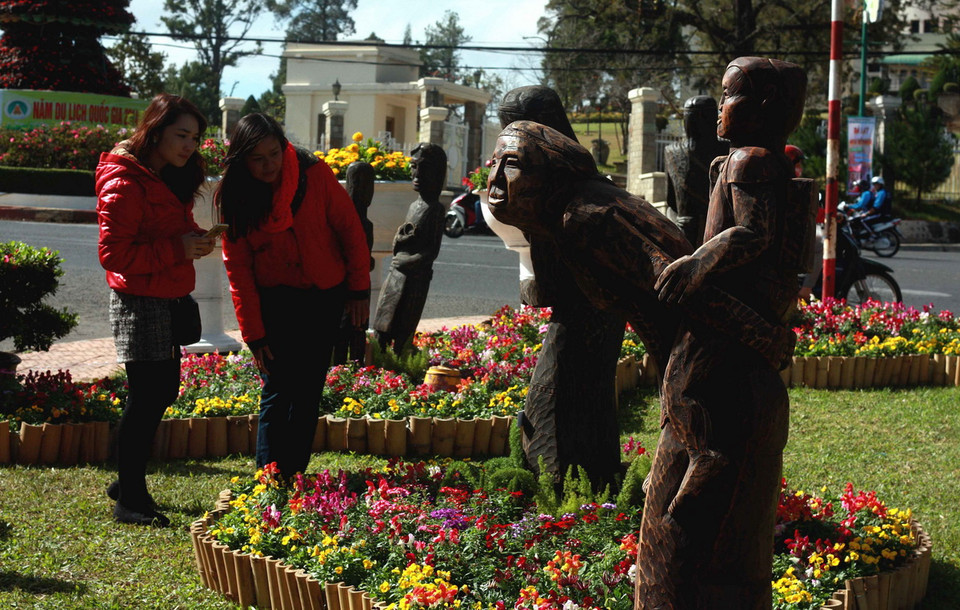 Tượng gỗ Tây Nguyên được sắp đặt chung với hoa Đà Lạt trong không gian “Đà Lạt bốn mùa hoa." (Ảnh: Nguyễn Dũng - TTXVN) 