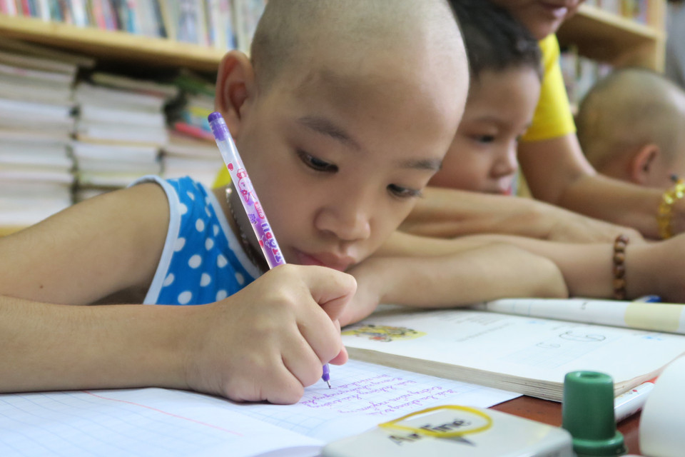 Bệnh nhi ung thư miệt mài với từng con chữ. (Ảnh: Đinh Hằng/TTXVN)