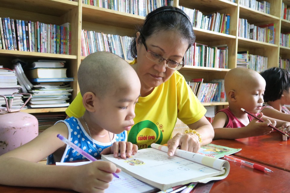 Giáo viên tình nguyện dạy chữ cho bệnh nhi tại “lớp học ung bướu.” (Ảnh: Đinh Hằng/TTXVN)
