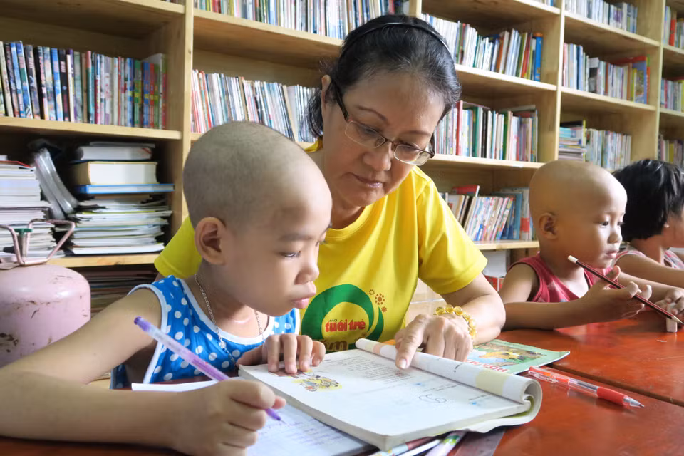 Giáo viên tình nguyện dạy chữ cho bệnh nhi tại “lớp học ung bướu.” (Ảnh: Đinh Hằng/TTXVN)