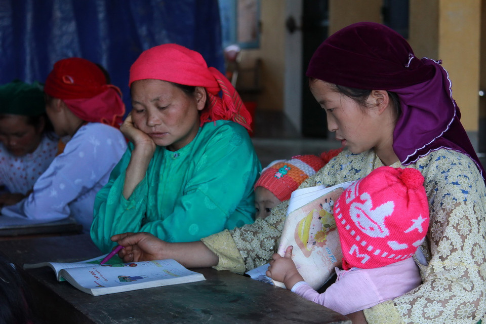 Nhiều chị em phụ nữ dân tộc Mông ở xã Sảng Tủng vừa học cái chữ vừa trông con nhỏ. (Ảnh: Đỗ Bình - TTXVN) 