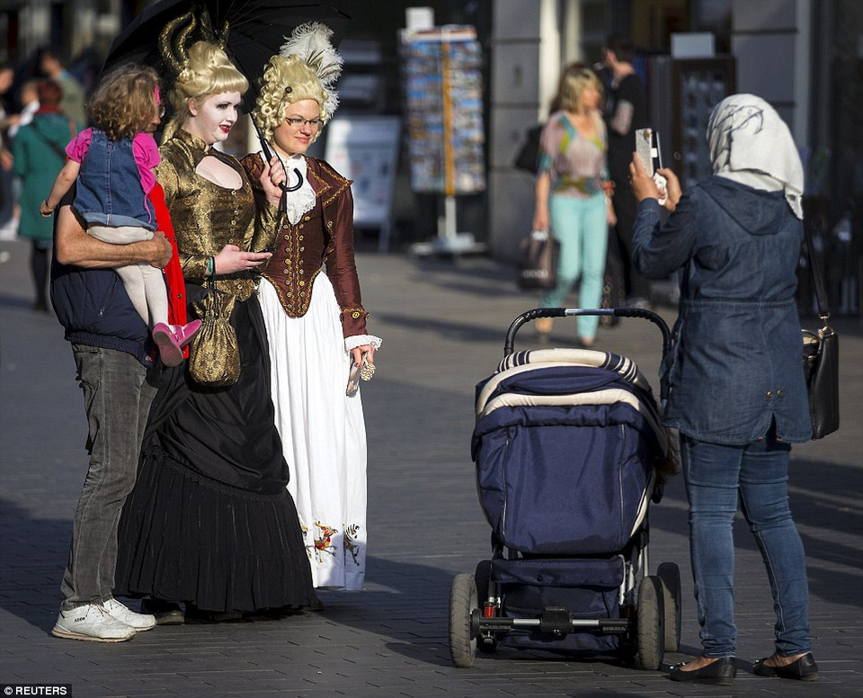 Một gia đình chụp ảnh cùng với những thành viên tham gia lễ hội Gothic đang đi qua nơi dành cho người đi bộ ở Leipzig. (Nguồn: dailymail.co.uk)