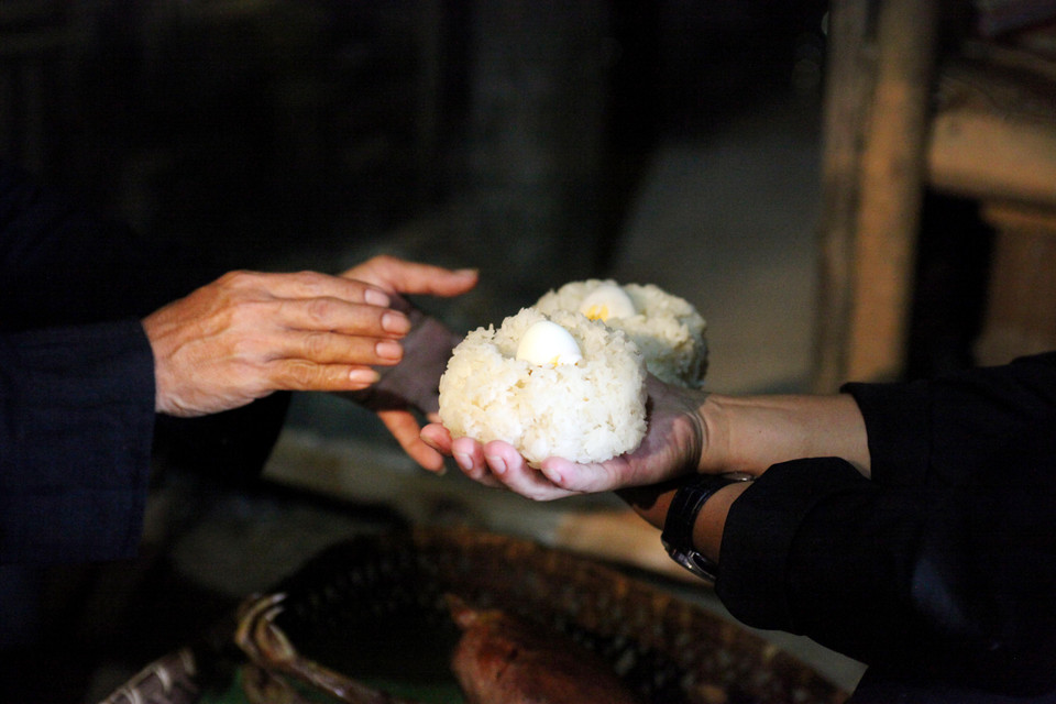 Sau nghi lễ này, chú rể bước ra, tay cầm xôi, tay cầm trứng mang ra cho cô dâu. Họ cùng nhau ăn hết xôi và trứng ngay tại cửa trước sự chứng kiến của tổ tiên cùng mọi người(Ảnh: Nhóm PV)