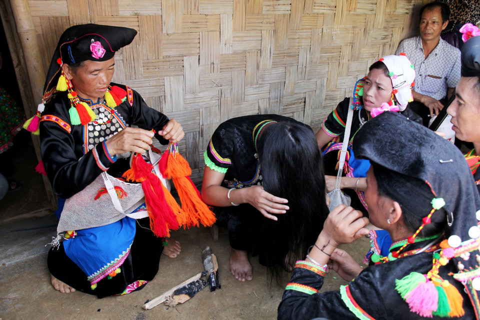 Khi đến cửa nhà trai, mọi người phải ngồi ngoài hiên chờ cho mẹ chồng lấy trang phục mới để cô dâu thay, gồm quần áo mới, khăn đội đầu và một số đồ trang sức. (Ảnh: Nhóm PV)