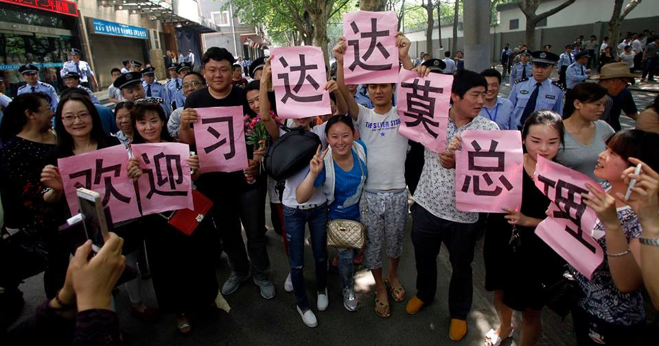 Một vài người chuẩn bị các khẩu hiệu để chào đón hai nhà lãnh đạo, những người khách thì cố kiếm một chỗ để chụp ảnh khi họ đi qua. (Nguồn: CCTVNews)