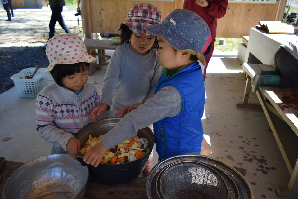 Các bé giúp nhau vác nồi. (Nguồn: Vietnam+)