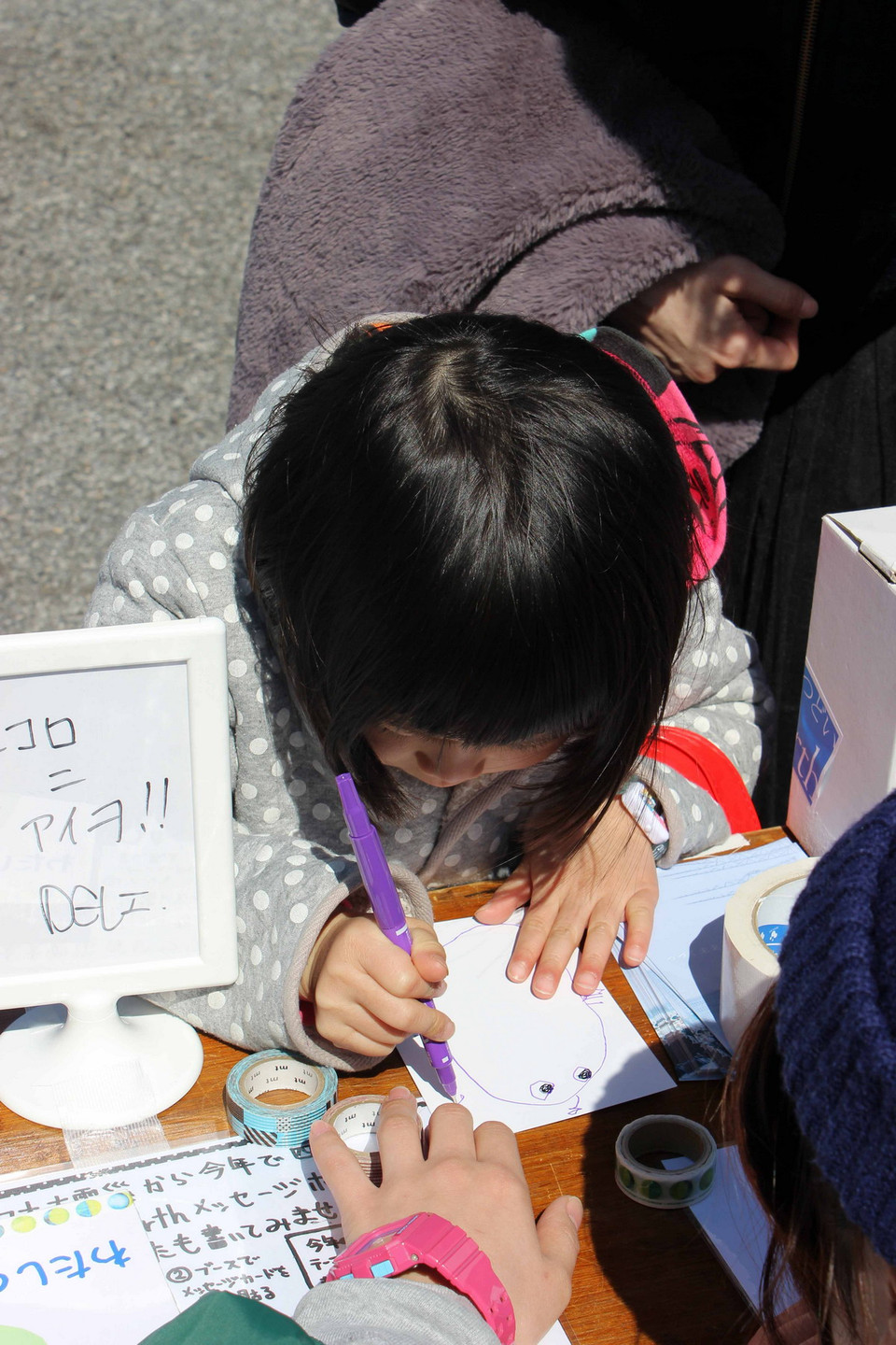 Một em nhỏ đang viết thông điệp gửi người dân vùng thảm hoạ. (Ảnh: Hữu Thắng/Vietnam+)