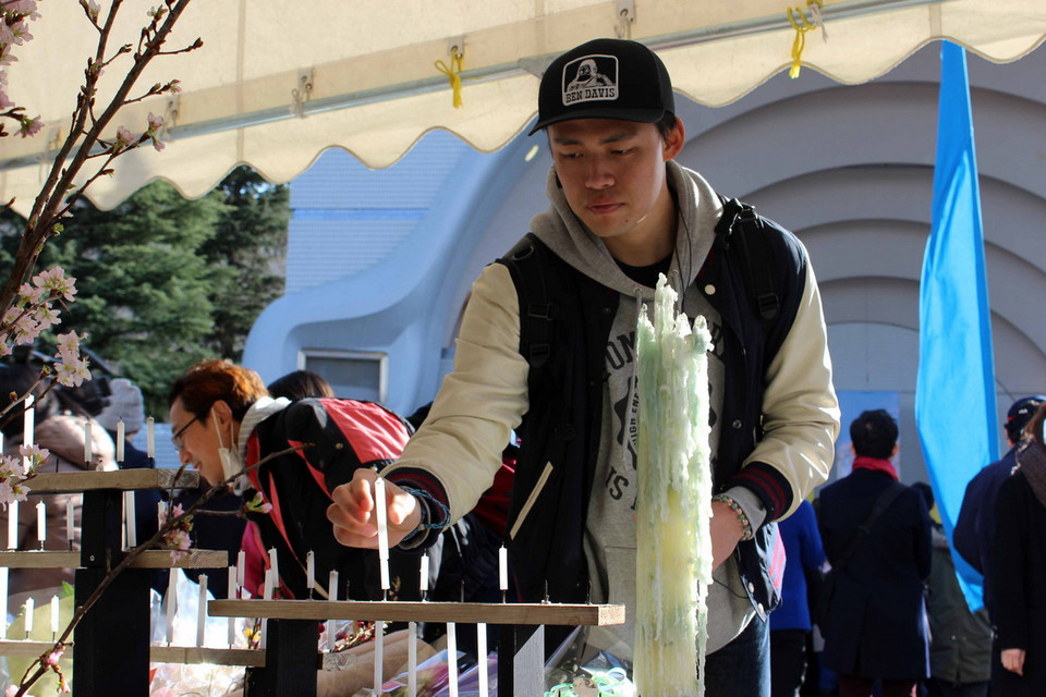 Từng người một lặng lẽ đặt hoa, thắp nến và cầu nguyện cho linh hồn các nạn nhân thảm hoạ động đất và sóng thần. (Ảnh: Hữu Thắng/Vietnam+)