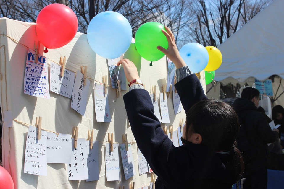 Một tình nguyện viên đang treo những quả bóng hy vọng lên tấm biển treo lời ước nguyện. (Ảnh: Hữu Thắng/Vietnam+)