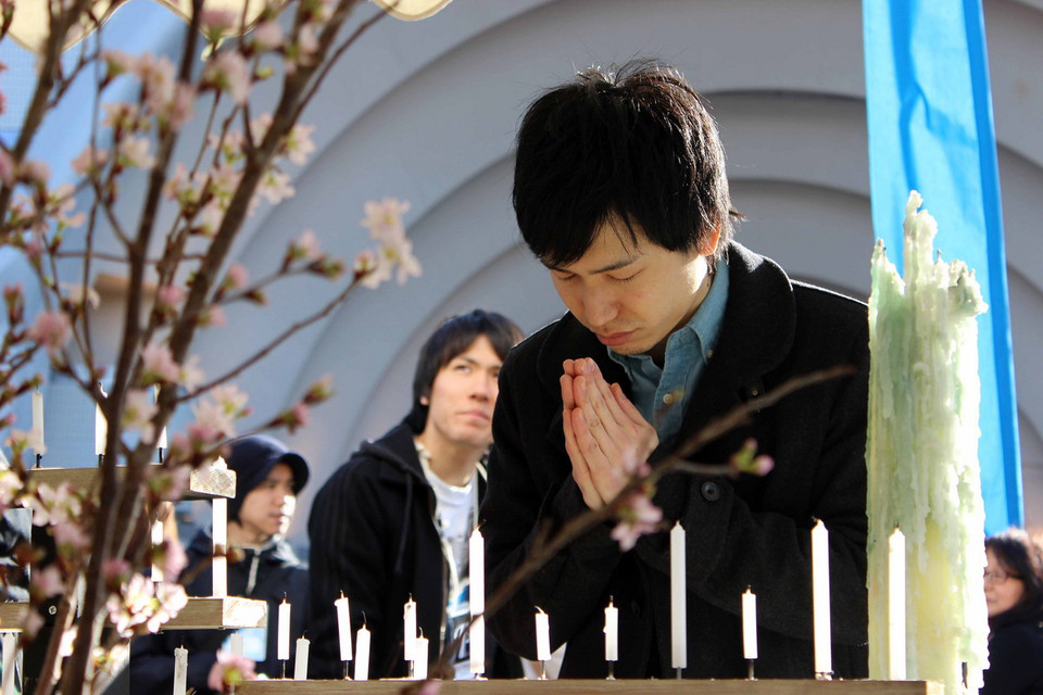 Một người tham dự chắp tay cầu nguyện cho các linh hồn nạn nhân xấu số trong thảm hoạ. (Ảnh: Hữu Thắng/Vietnam+)