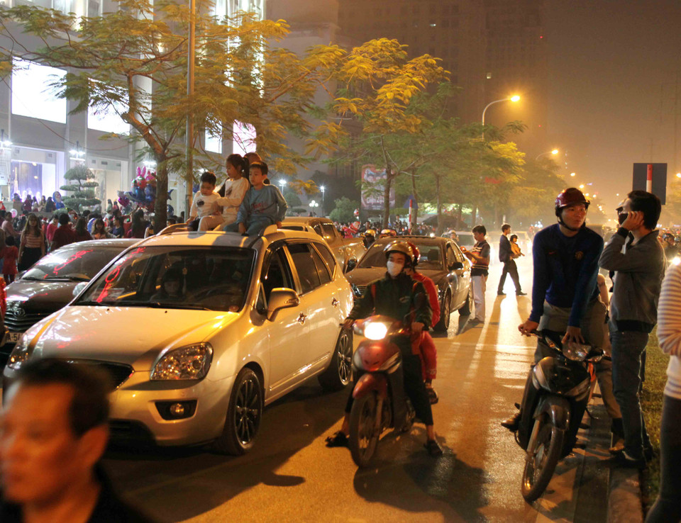 Một số gia đình đi ôtô đã vô tư đỗ trong làn đường dành cho xe máy, thậm chí còn mở cả nóc xe để cho các con lên xem. (Ảnh: Doãn Đức/Vietnam+)