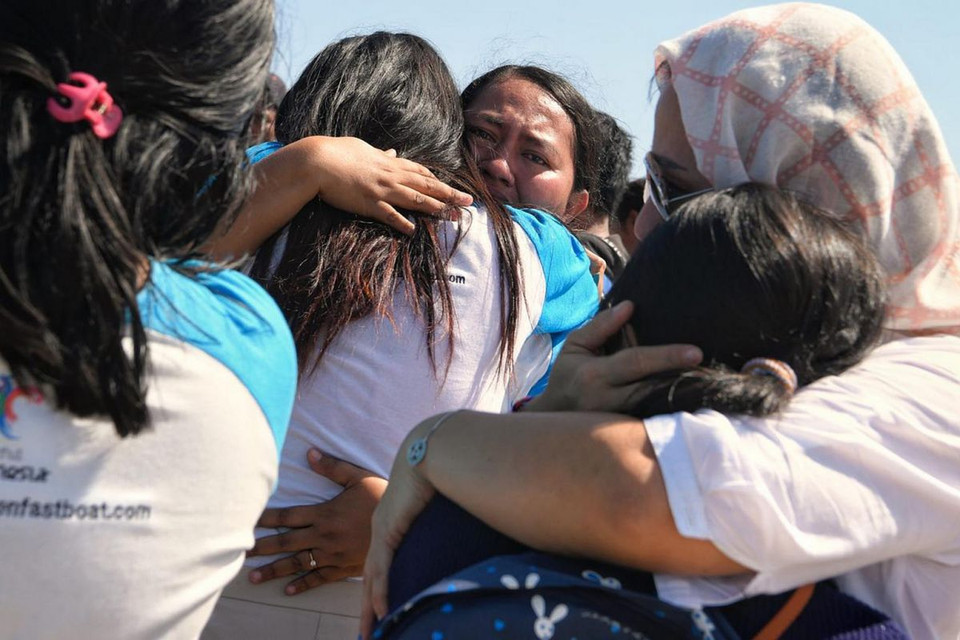 Nhân viên công ty dịch vụ thuyền Golden Queen Fastboat ôm các thành viên gia đình họ sau khi được lực lượng cứu hộ đưa đến cầu tàu Bangsal, ở Bắc Lombok, ngày 7/8.