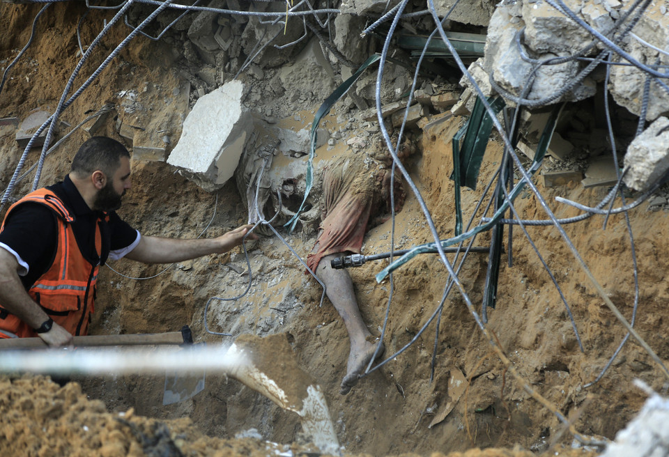 Nhân viên y tế Palestine tiếp cận một thi thể bị chôn vùi trong đống đổ nát của một ngôi nhà bị sập của gia đình al-Tanani ở Beit Lahia, phía bắc Dải Gaza. (Ảnh: AFP)