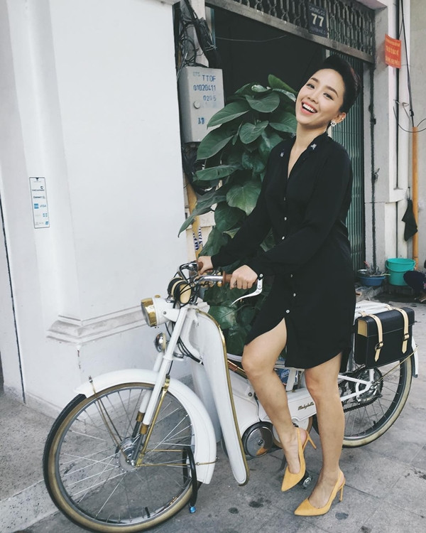 Tóc Tiên tạo dáng nghịch ngợm cùng xe máy cổ. Chủ nhân 'Vũ điệu cồng chiêng' khoe vẻ tươi tắn trong mẫu đầm sơmi đen và đôi giày cao gót quai hậu (slingback).