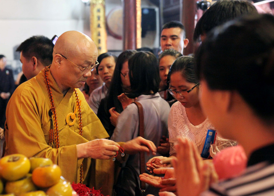 Hòa thượng Thích Thanh Nhã trao tặng vòng đeo cổ 4 lá cho những người tham gia chương trình. (Ảnh: Doãn Đức/Vietnam+)