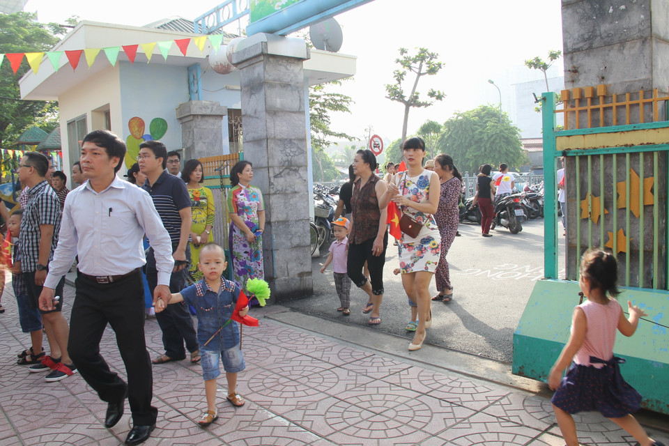 Ngay từ 7 giờ sáng các em học sinh cùng phu huynh đã bắt đầu có mặt tại trường mầm non Yên Hòa để tham dự lễ khai giảng năm học mới, trên tay các em đều cầm cờ và hoa để mang tới bầu không khí lễ hội cho ngày tựu trường. (Ảnh: Tiến Đạt/Vietnam+)