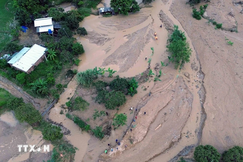 Lực lượng chức năng đã bố trí người cắm thiết bị cảnh bảo ở các điểm sạt lở cho các phương tiện giao thông đi qua. (Ảnh: Văn Tý/TTXVN)