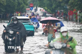 Chân dốc Minh Khai mênh mông nước, người dân gặp nhiều khó khăn khi cố gắng di chuyển. (Ảnh: Thanh Tùng/TTXVN)
