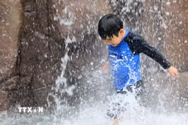 Em nhỏ làm mát dưới đài phun nước ở Incheon, Hàn Quốc ngày 13/7. (Ảnh: Yonhap/TTXVN)